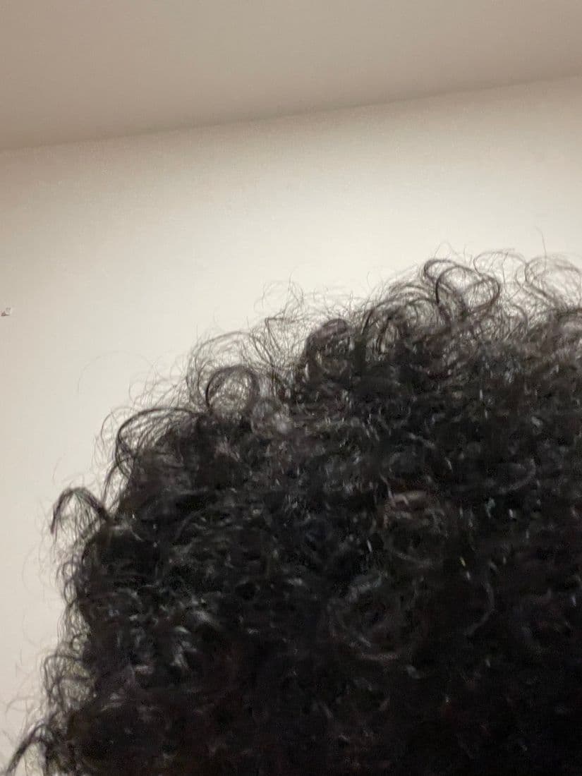 Fingers parting the hair to apply serum to a thinning area